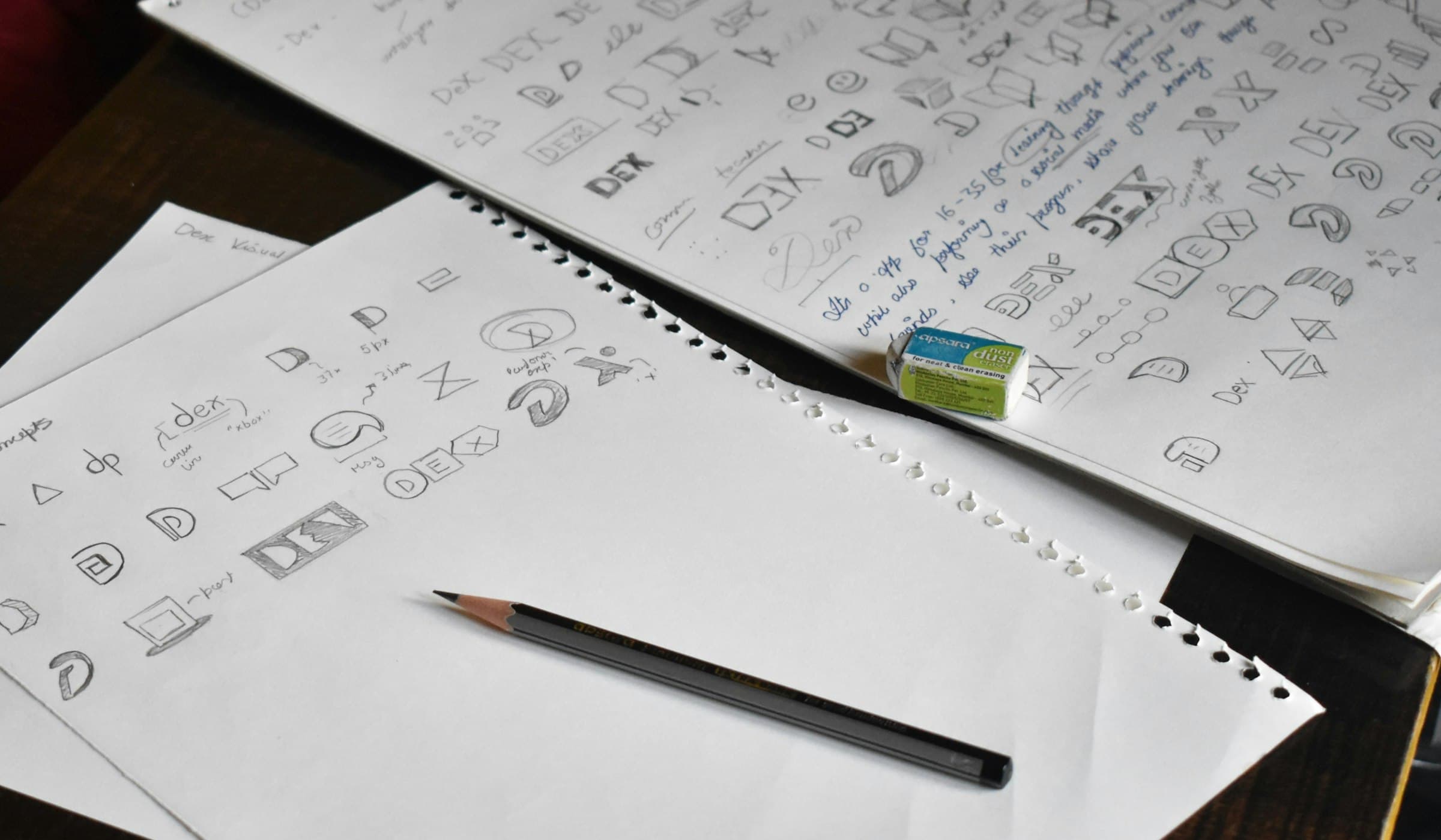 Pencil logo concept sketches on paper.